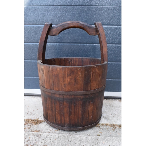 284 - A coopered wooden well bucket with metal bands. 51cm tall. Some age-related wear and tear to include... 