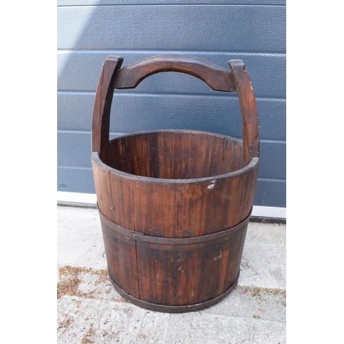 284 - A coopered wooden well bucket with metal bands. 51cm tall. Some age-related wear and tear to include... 