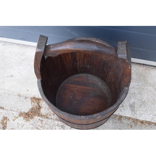 284 - A coopered wooden well bucket with metal bands. 51cm tall. Some age-related wear and tear to include... 