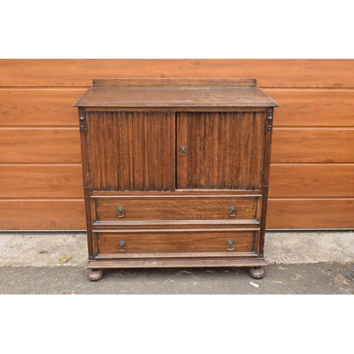 291 - 1930s oak Priory style cupboard over 2 draws raised on feet. 99 x 54 x 103.In good functional condit... 