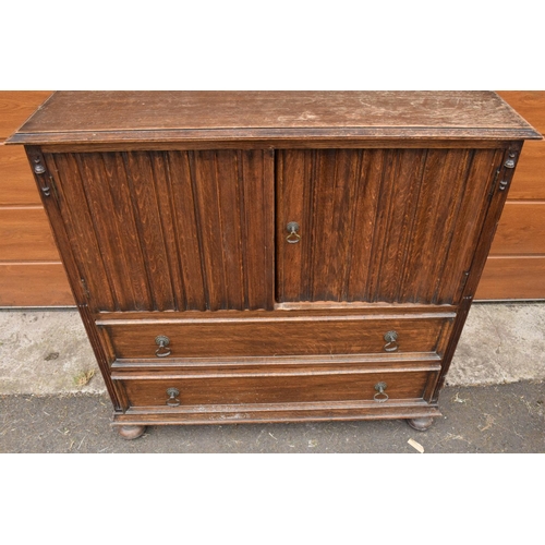 291 - 1930s oak Priory style cupboard over 2 draws raised on feet. 99 x 54 x 103.In good functional condit... 