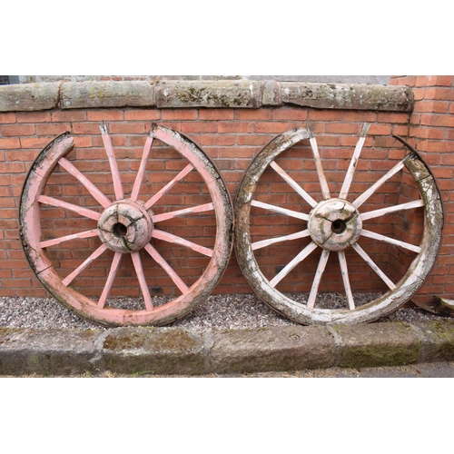 318 - A pair of early 20th century cart wheels with metal rims in a painted pink colour. 130cm diameter. T... 