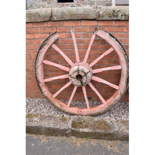 318 - A pair of early 20th century cart wheels with metal rims in a painted pink colour. 130cm diameter. T... 