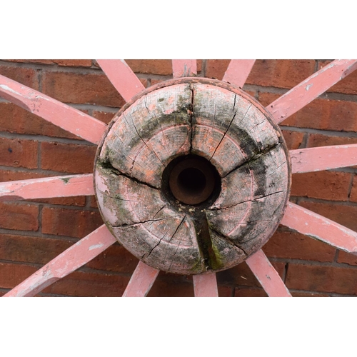 318 - A pair of early 20th century cart wheels with metal rims in a painted pink colour. 130cm diameter. T... 