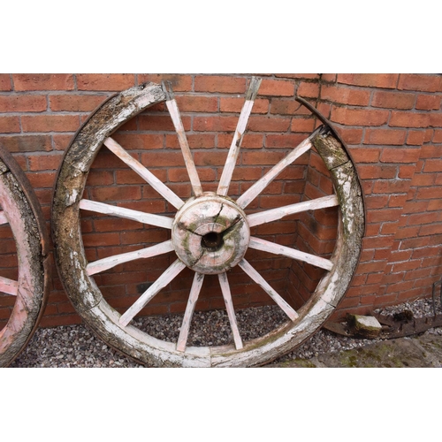 318 - A pair of early 20th century cart wheels with metal rims in a painted pink colour. 130cm diameter. T... 