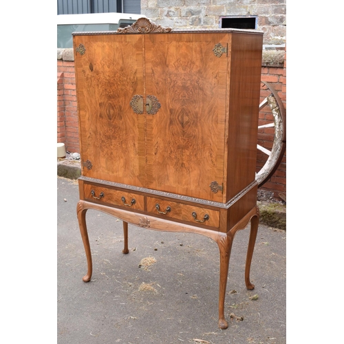 319 - An early 20th Century Queen Anne style walnut drinks / cocktail cabinet with the doors opening to re... 