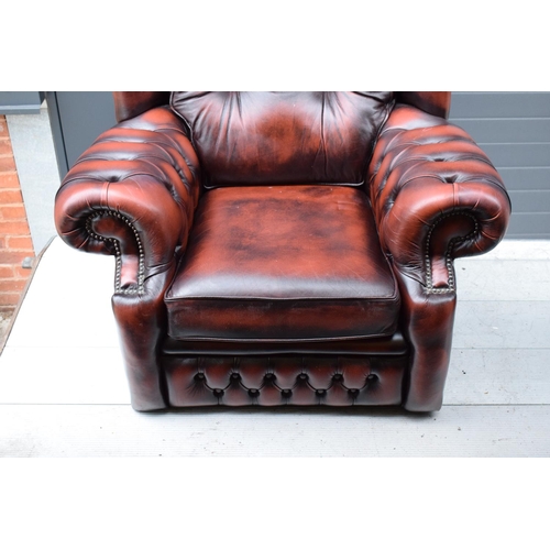 388 - A modern Chesterfield style wingback armchair with button back design raised on 4 wooden feet in oxb... 