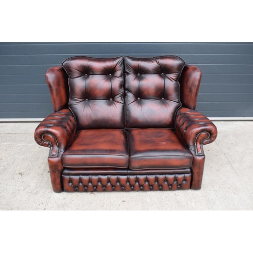 389 - A modern Chesterfield style two-seater sofa with button-back design in oxblood red. In good function... 