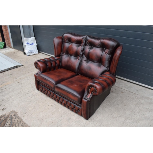 389 - A modern Chesterfield style two-seater sofa with button-back design in oxblood red. In good function... 