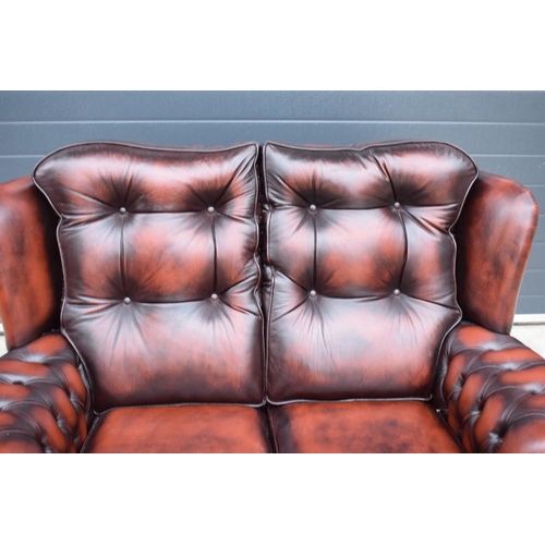 389 - A modern Chesterfield style two-seater sofa with button-back design in oxblood red. In good function... 