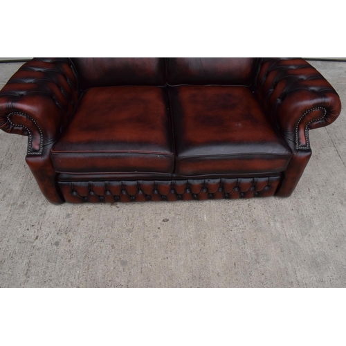 389 - A modern Chesterfield style two-seater sofa with button-back design in oxblood red. In good function... 