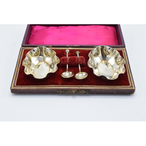 215F - A silver plated cased set of table salts and spoons.