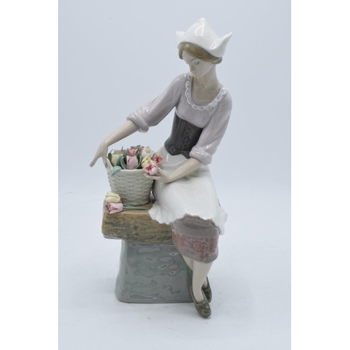 44 - Lladro figurine of a Dutch Girl sat with a basket of flowers. 26cm tall. In good condition with no o... 