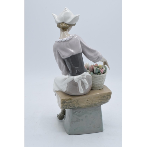 44 - Lladro figurine of a Dutch Girl sat with a basket of flowers. 26cm tall. In good condition with no o... 