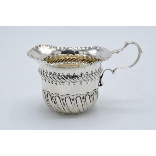 333 - An ornate silver cream jug / sauce jug. London 1890.  53.7 grams. In good condition with some dents ... 