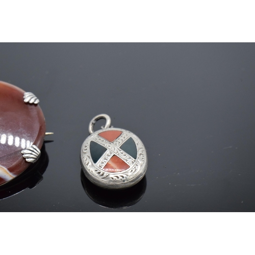 555 - A silver and agate circular brooch together with an agate set locket-back pendant (2).