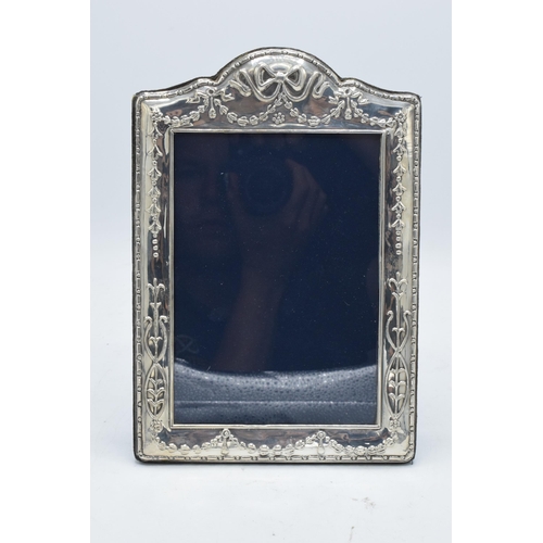 244 - A large hallmarked silver photo frame with embossed decoration. 24.5cm tall. Easel backed. Sheffield... 