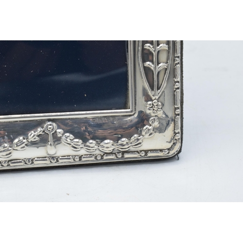 244 - A large hallmarked silver photo frame with embossed decoration. 24.5cm tall. Easel backed. Sheffield... 