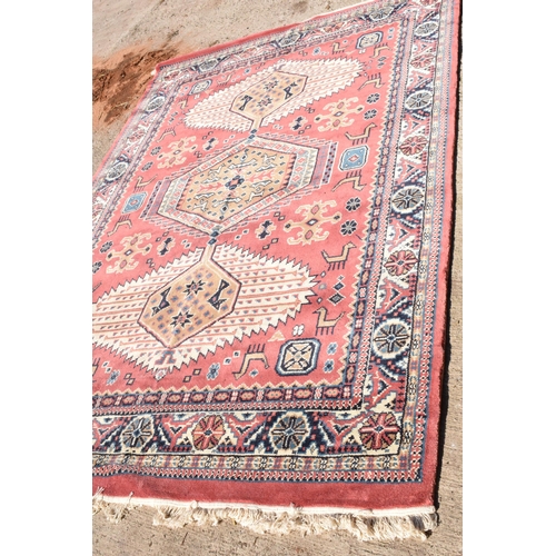 285 - A 20th century carpet decorated in a red / pink colour. Approx 276 x 180cm.