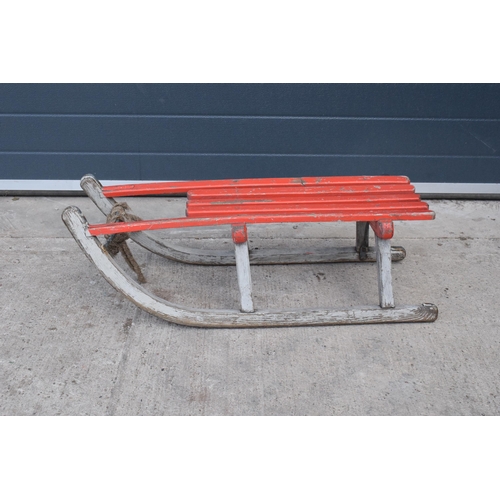 276 - A vintage wooden child's sledge painted in red by Henry A Murton of Newcastle. 82cm long. In good co... 