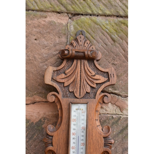 298 - A late Victorian/ Edwardian arts and crafts style carved aneroid barometer. 105cm tall. There are so... 