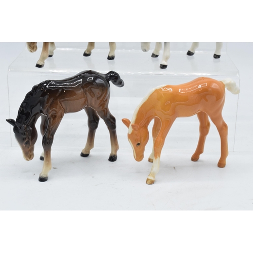 164 - A collection of Beswick ponies to include grazing pony 946 in palomino, 3 brown examples and a dappl... 