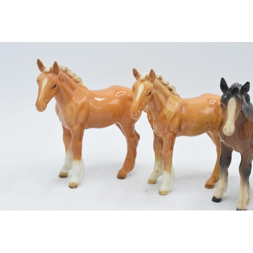 165 - A collection of Beswick shire foals 1053 to include 2 brown examples and 2 palomino examples (4). In... 