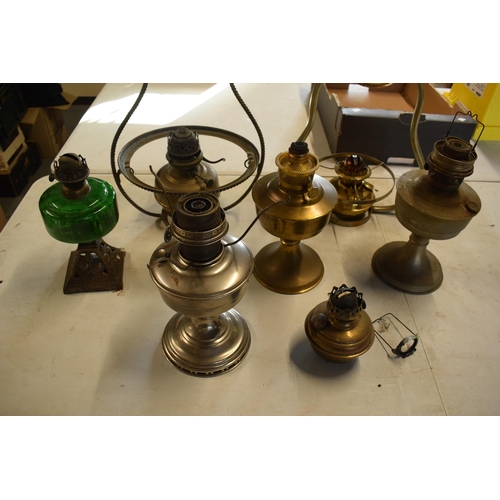 287 - A collection of 20th century oil lamps and burners of various forms to include examples with swingin... 