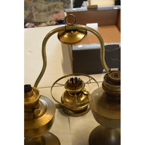 287 - A collection of 20th century oil lamps and burners of various forms to include examples with swingin... 