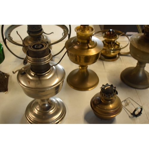 287 - A collection of 20th century oil lamps and burners of various forms to include examples with swingin... 