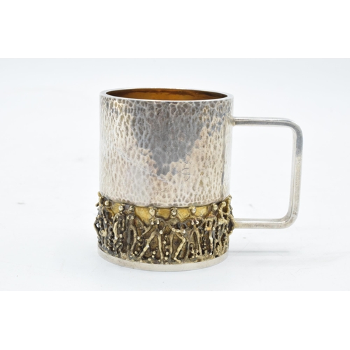 249 - Stuart Devlin: A silver and silver gilt tankard / cup with figural decoration to the bottom half of ... 
