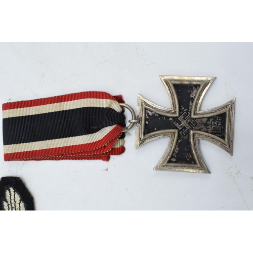 273 - A collection of German Militaria to include a WW2 iron cross and ribbon, a reproduction Nazi cap bad... 