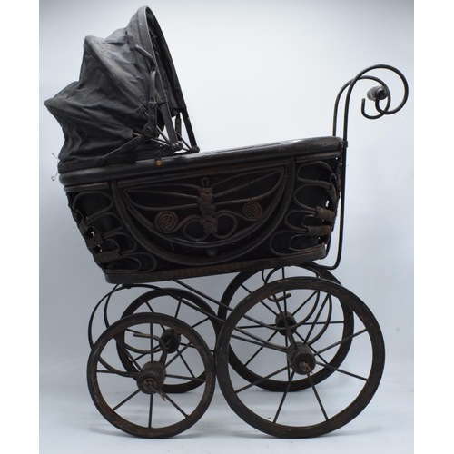 316 - Am early to mid 20th century ornate dolls pram on wooden and metal wheels. 58cm tall.