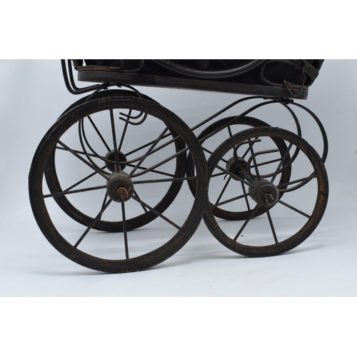 316 - Am early to mid 20th century ornate dolls pram on wooden and metal wheels. 58cm tall.