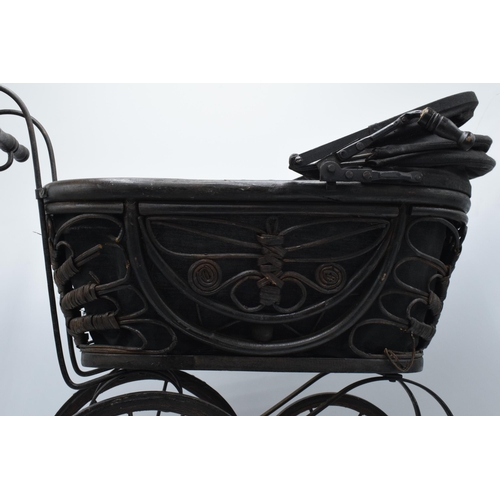 316 - Am early to mid 20th century ornate dolls pram on wooden and metal wheels. 58cm tall.