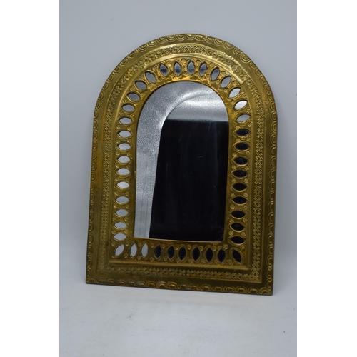 334 - A 20th century arched brass mirror with embossed decoration. 37 x 27cm.