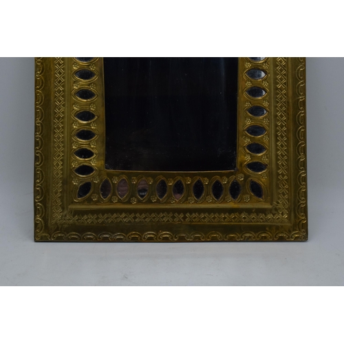 334 - A 20th century arched brass mirror with embossed decoration. 37 x 27cm.