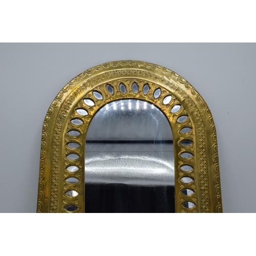 334 - A 20th century arched brass mirror with embossed decoration. 37 x 27cm.