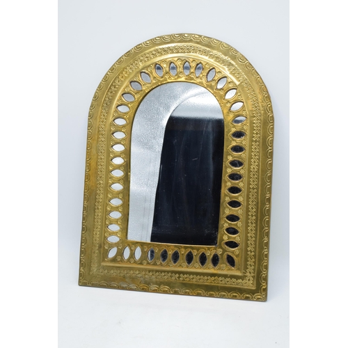 334 - A 20th century arched brass mirror with embossed decoration. 37 x 27cm.