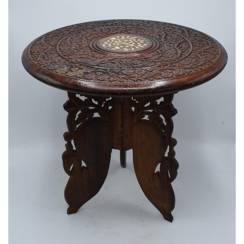 335 - A 20th century Middle Eastern collapsible wooden table with carved and inlaid decoration. 39cm tall.... 