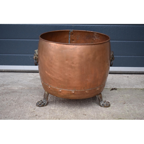 362 - A large early 20th century copper and brass cauldron / log basket with lion's head handles and claw ... 