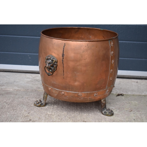 362 - A large early 20th century copper and brass cauldron / log basket with lion's head handles and claw ... 