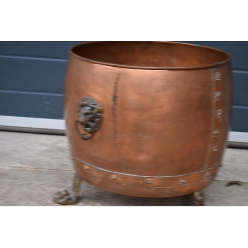 362 - A large early 20th century copper and brass cauldron / log basket with lion's head handles and claw ... 