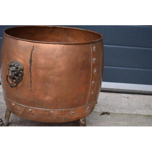 362 - A large early 20th century copper and brass cauldron / log basket with lion's head handles and claw ... 