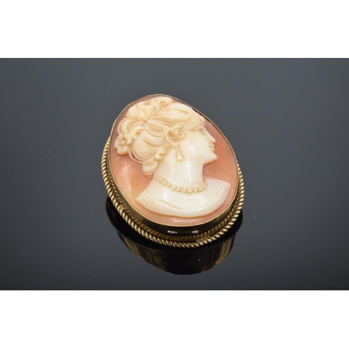 224 - 9ct gold cased cameo pendant / brooch of a lady looking right. 7.0 grams gross weight. 3cm tall.