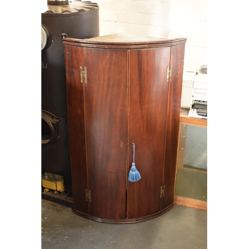 299 - A 19th century inlaid mahogany bow fronted corner cupboard. 111cm tall. Brass 'H' hinges. In good fu... 