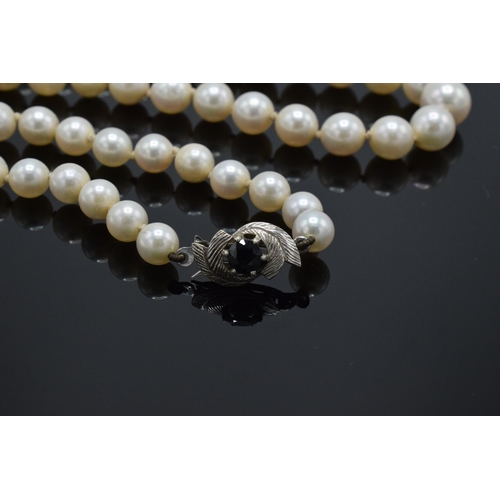 424 - A single-string pearl necklace with a fully hallmarked 9ct white gold clasp set with a sapphire ston... 