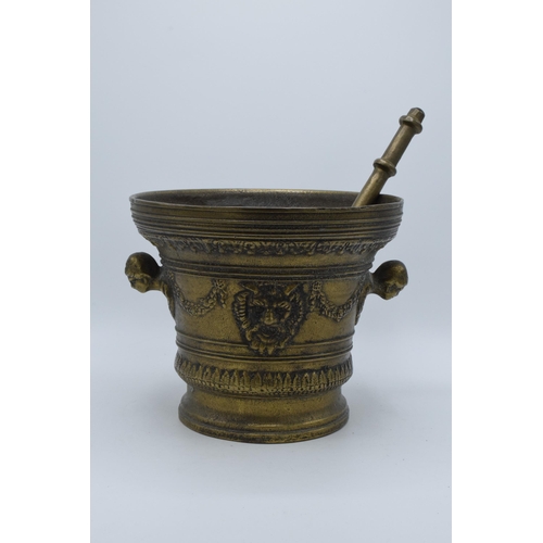 421 - A large antique cast brass mortar and pestle with ornate decoration featuring the devils face. 21cm ... 