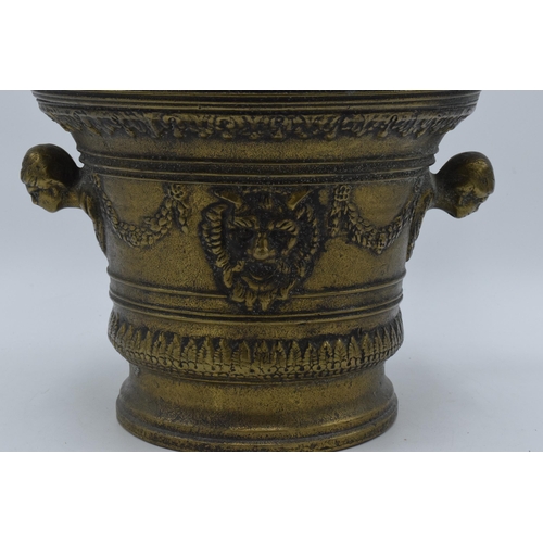 421 - A large antique cast brass mortar and pestle with ornate decoration featuring the devils face. 21cm ... 