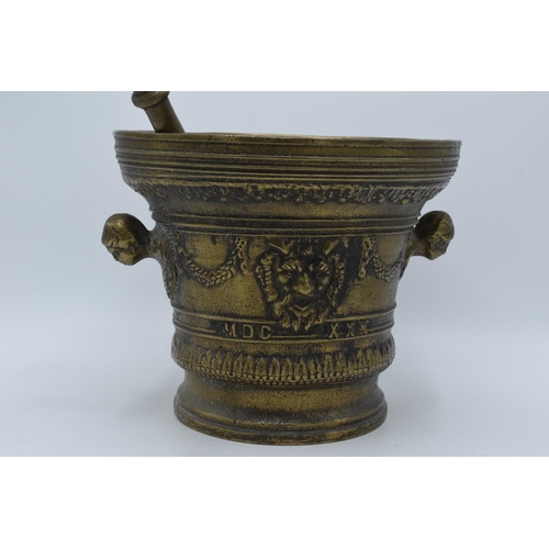 421 - A large antique cast brass mortar and pestle with ornate decoration featuring the devils face. 21cm ... 